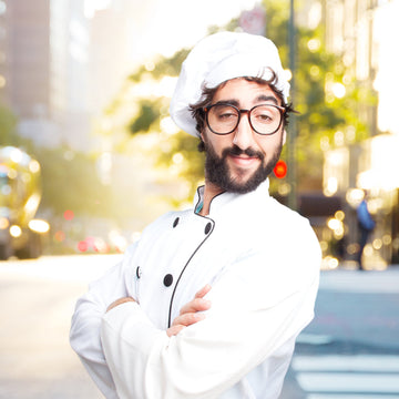 Person wearing a chef's outfit with a blurred city street background