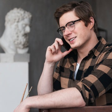 Man talking on a phone with a sculpture in the background