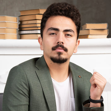 Man in a green blazer sitting in front of stacked books